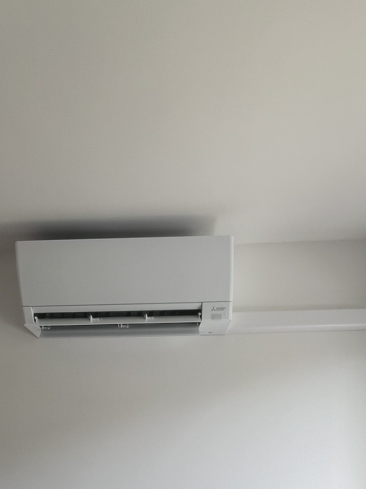 Unité murale Mitsubishi Electric sous plafond avec goulotte courte vers la fenêtre